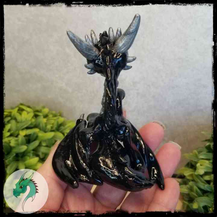 View of the back of a black clay dragon held in a hand