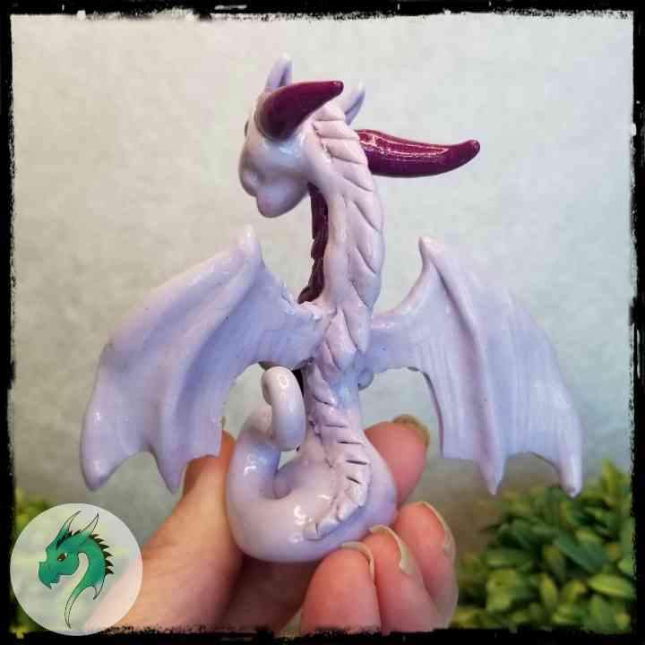 Back view of a hand holding a clay dragon