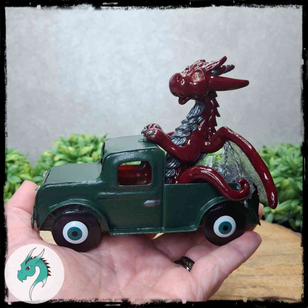 Hand holding a clay dragon in a green truck