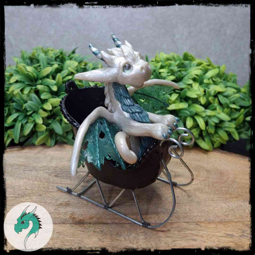 A hand holding a clay dragon inside a sleigh