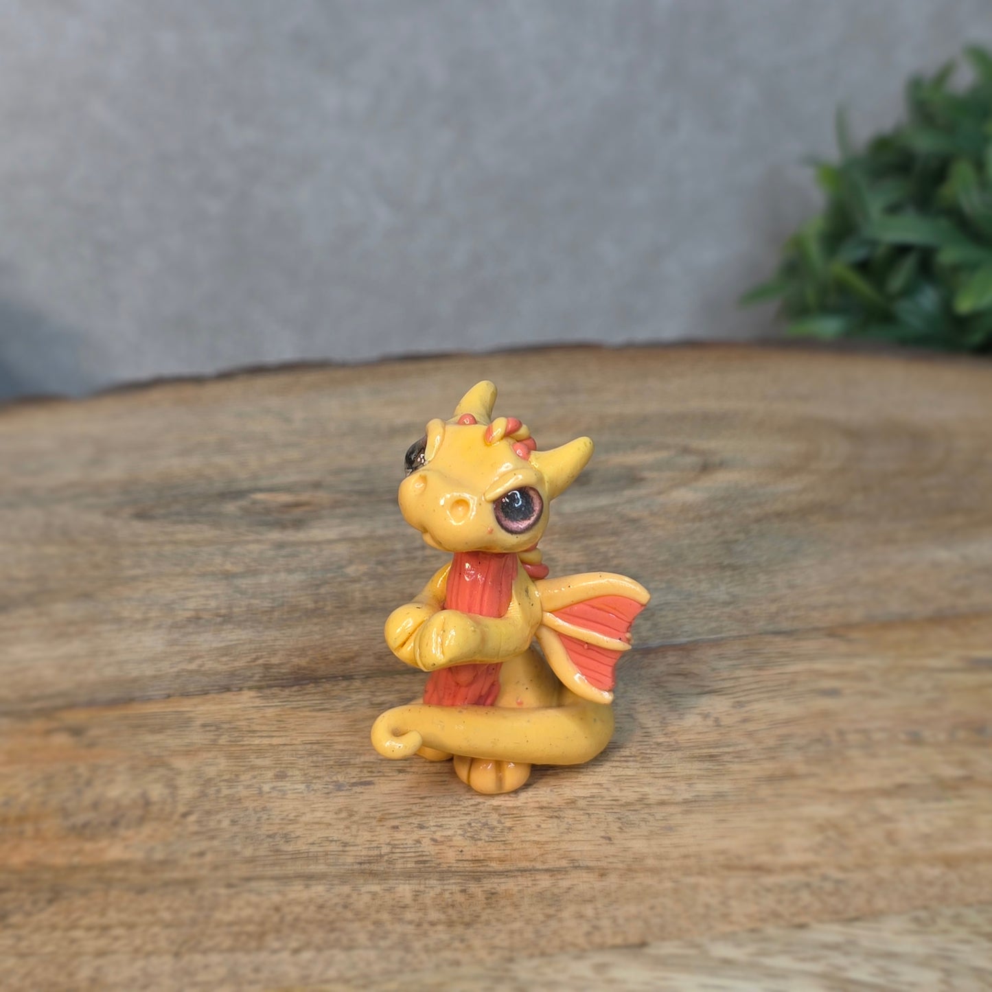 A small peach dragon against a blurred wood background