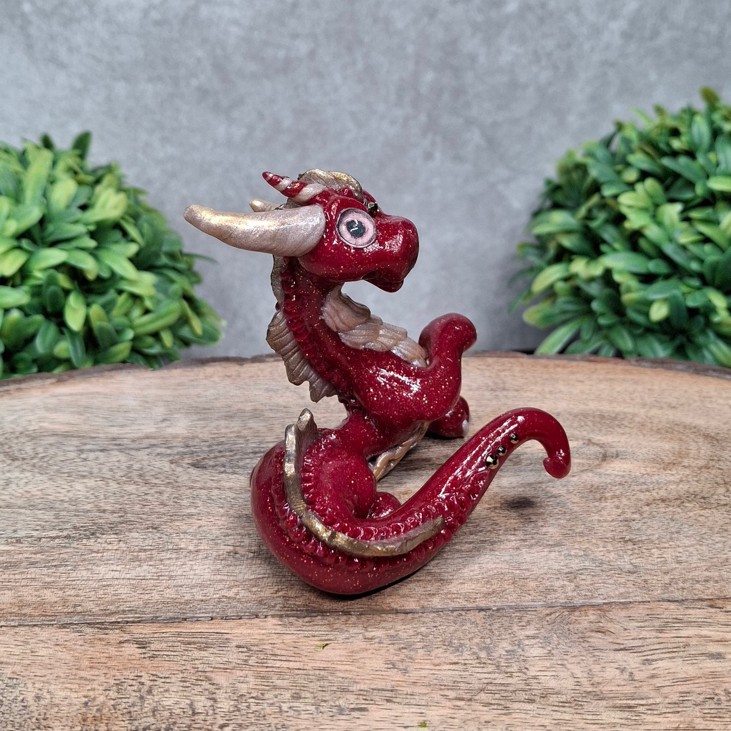 A clay dragon against a wood background with greenery