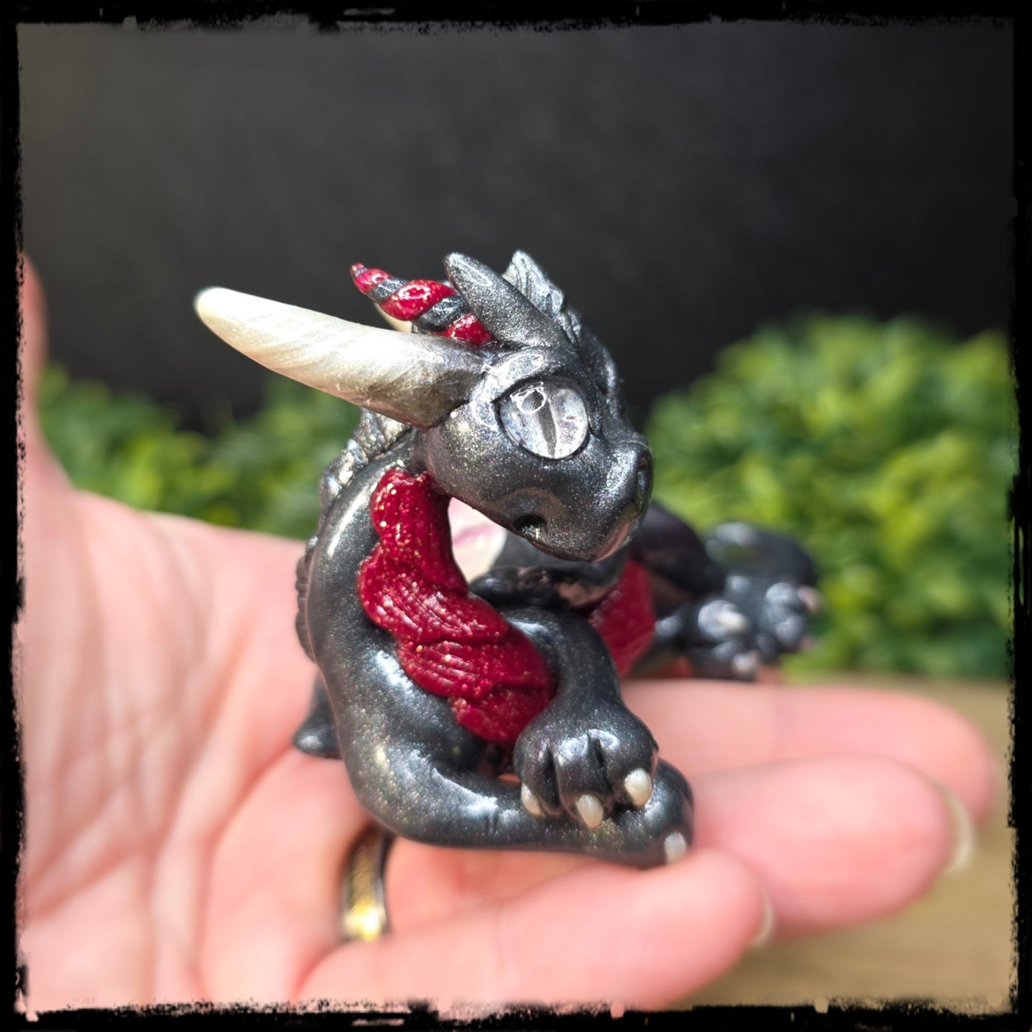 Small dragon figurine held in a hand against a blurred green background