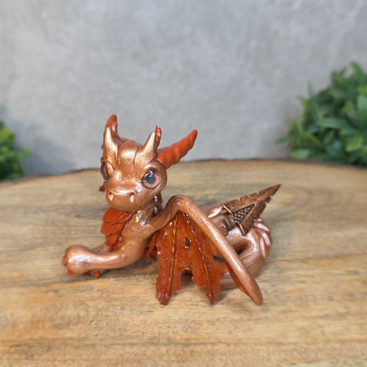 Copper dragon figurine on a wood surface with a blurred background