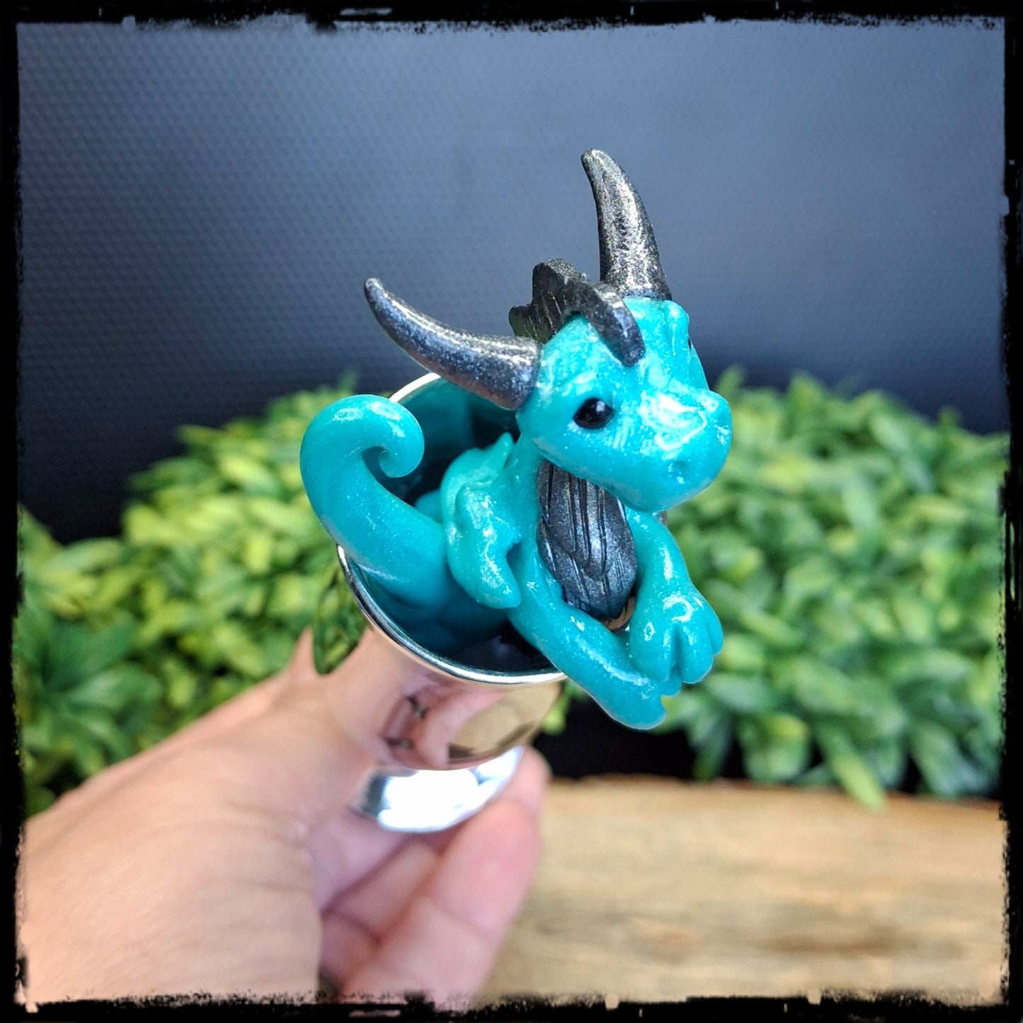 Hand holding a blue dragon inside a tall shot glass
