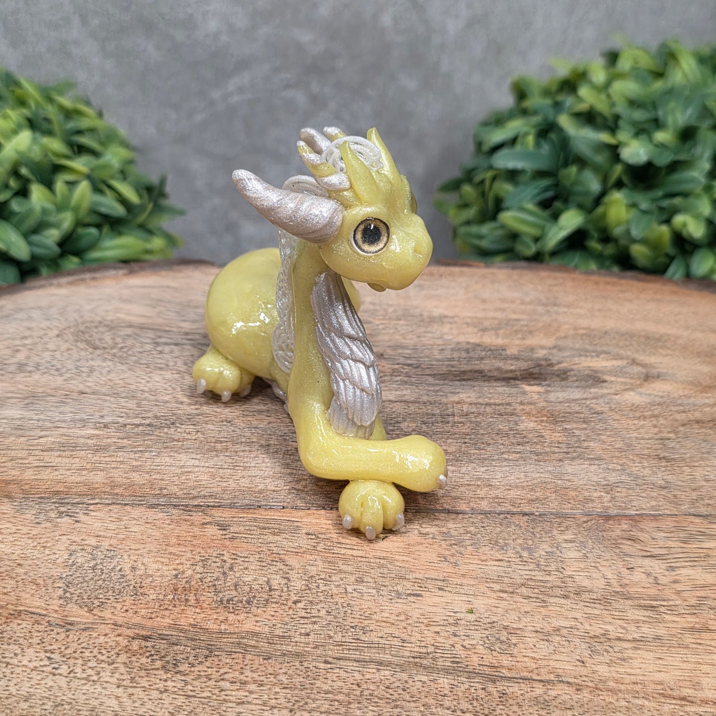 A dragon sculpture on wood surface with greenery