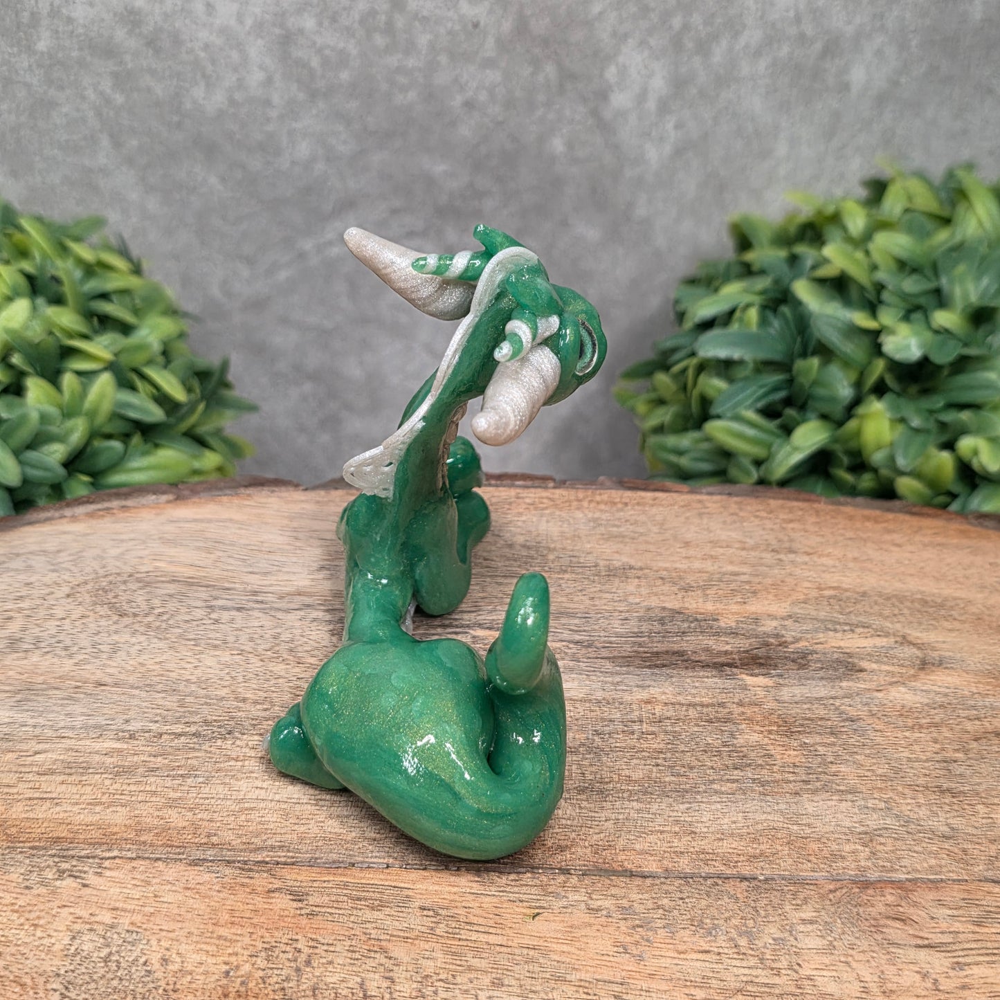 A dragon sculpture on wood surface with greenery