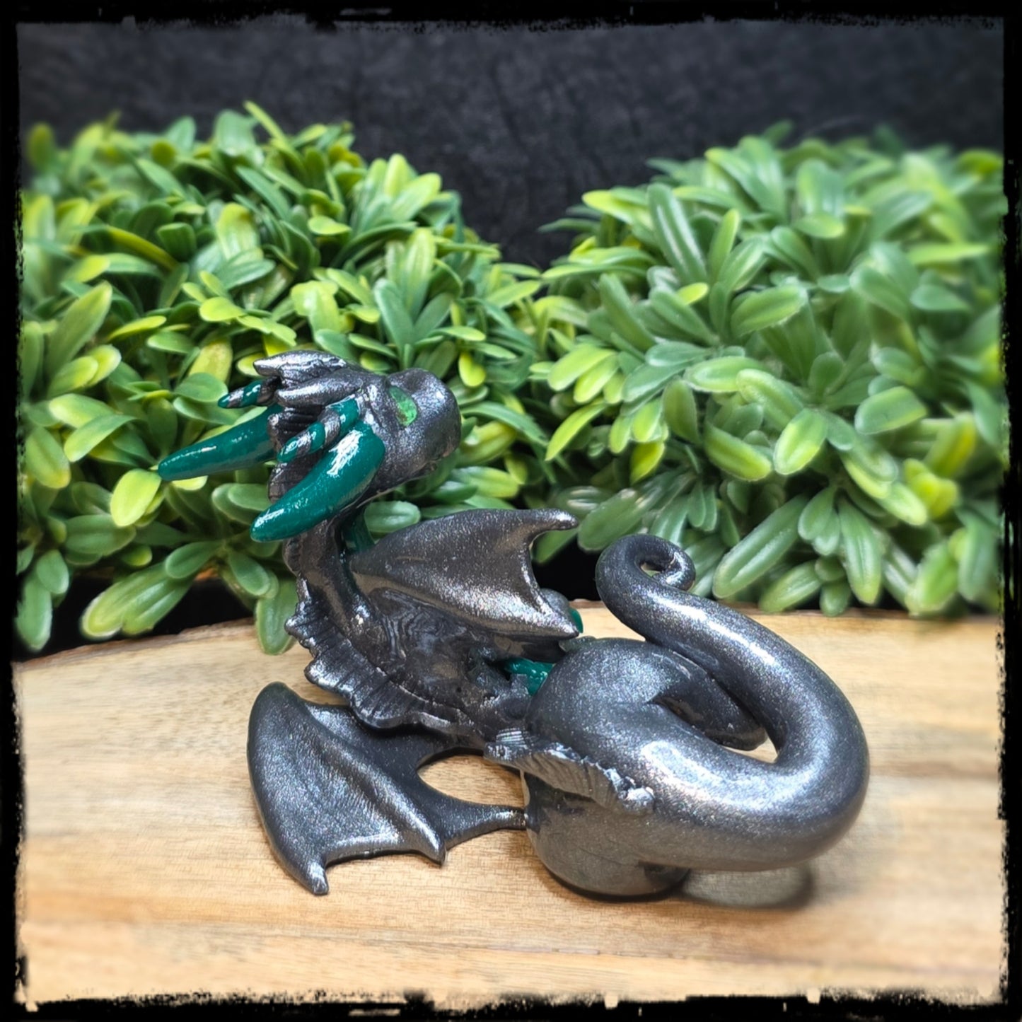 Clay dragon on wood surface against a leafy background
