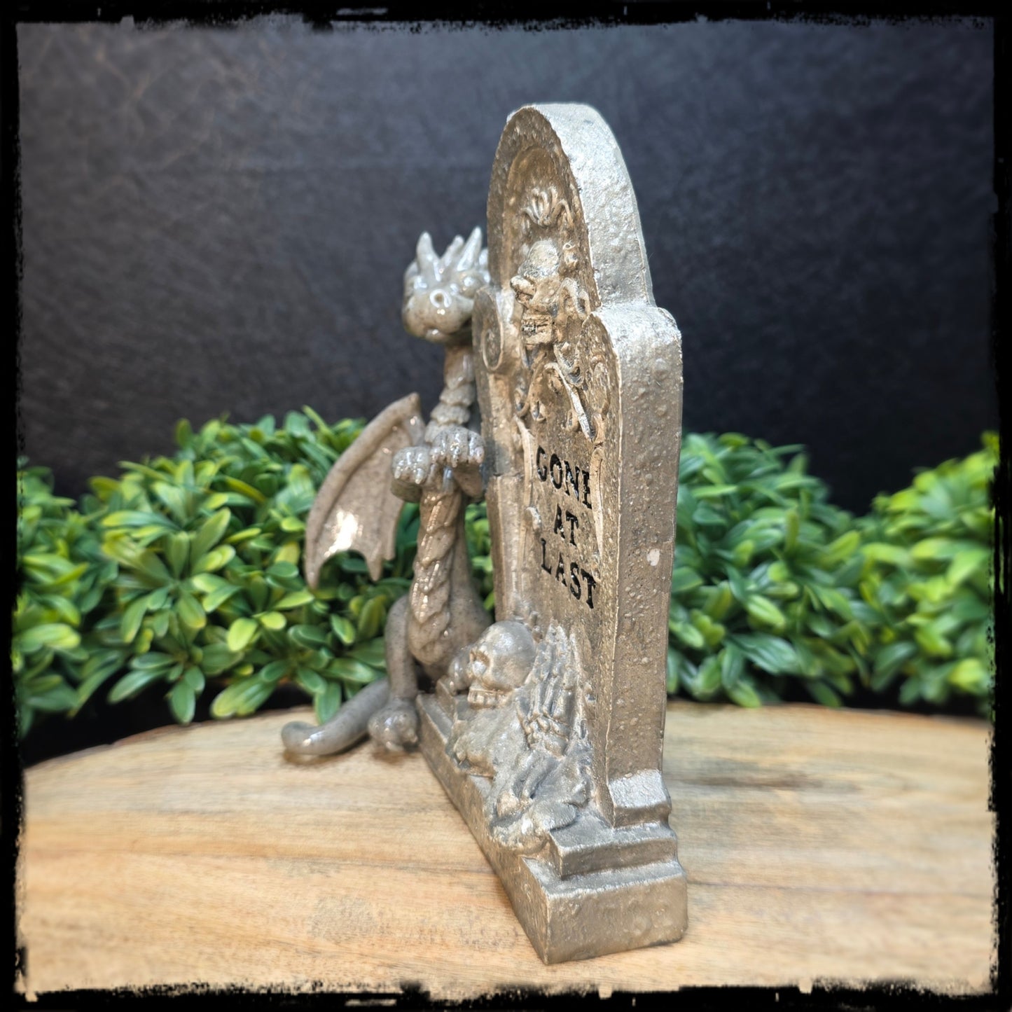 Decorative figurine of a dragon and tombstone with text on a wooden surface.