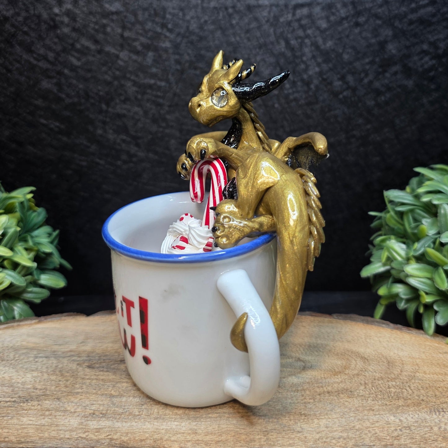 Gold dragon figurine with candy canes on a mug against a dark background