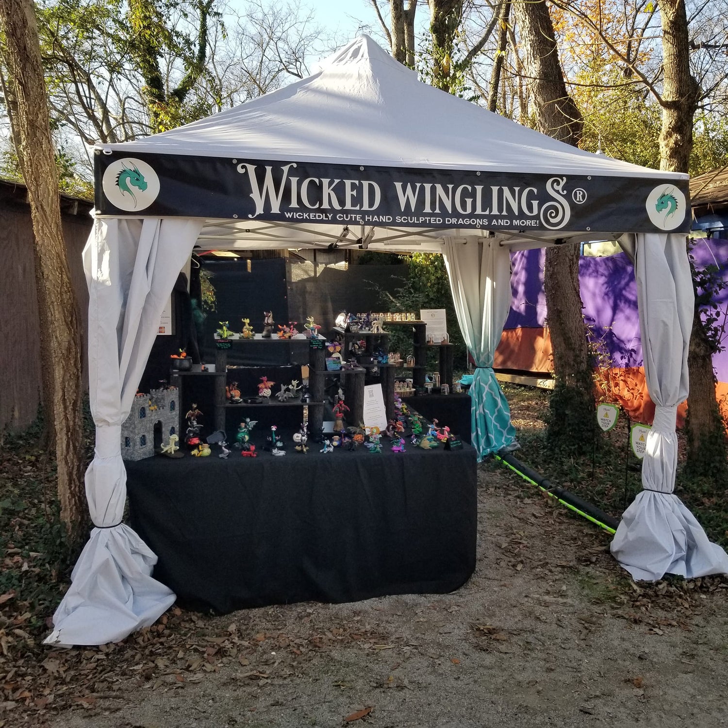 Wicked Winglings booth with figurines under a canopy in an outdoor setting