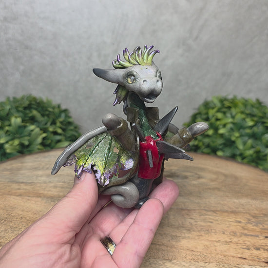 Video of a hand holding a clay dragon in a costume