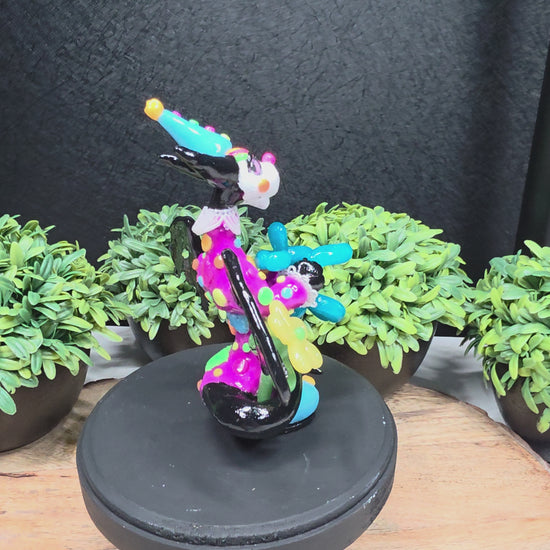 A video of a clown dragon with balloon animals on wood surface with greenery