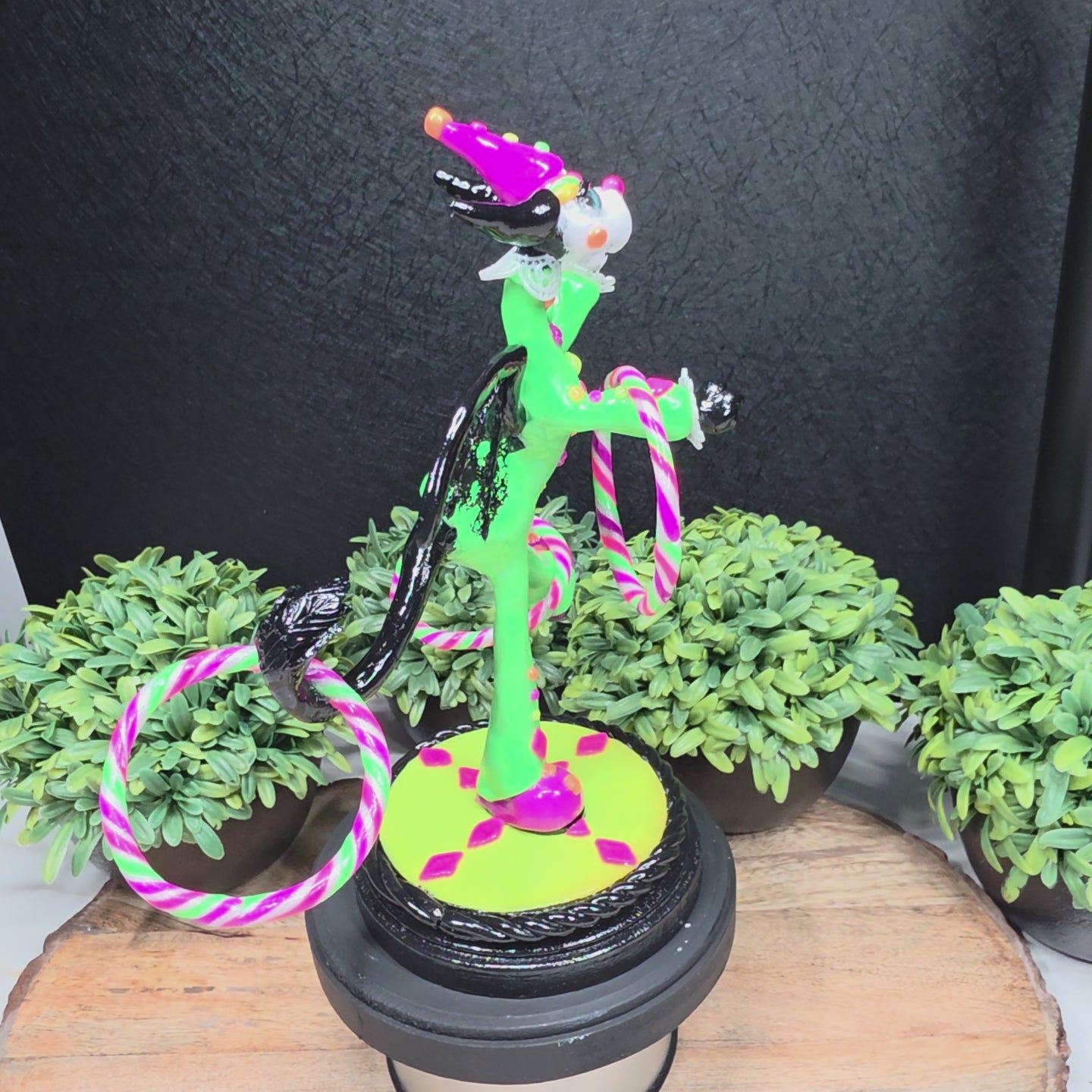 A video of a clown dragon with hoola hoops on a wood surface with greenery