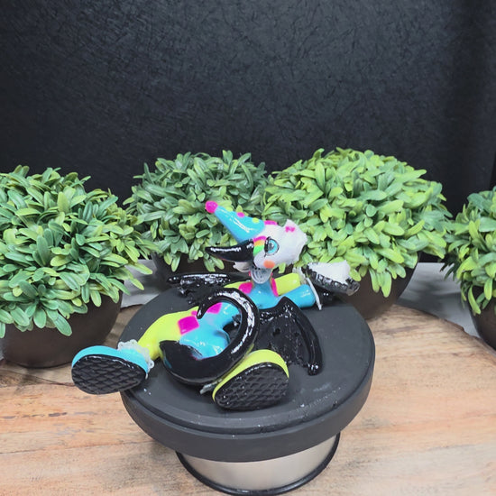 A video of a clown dragon with a cream pie on face against greenery