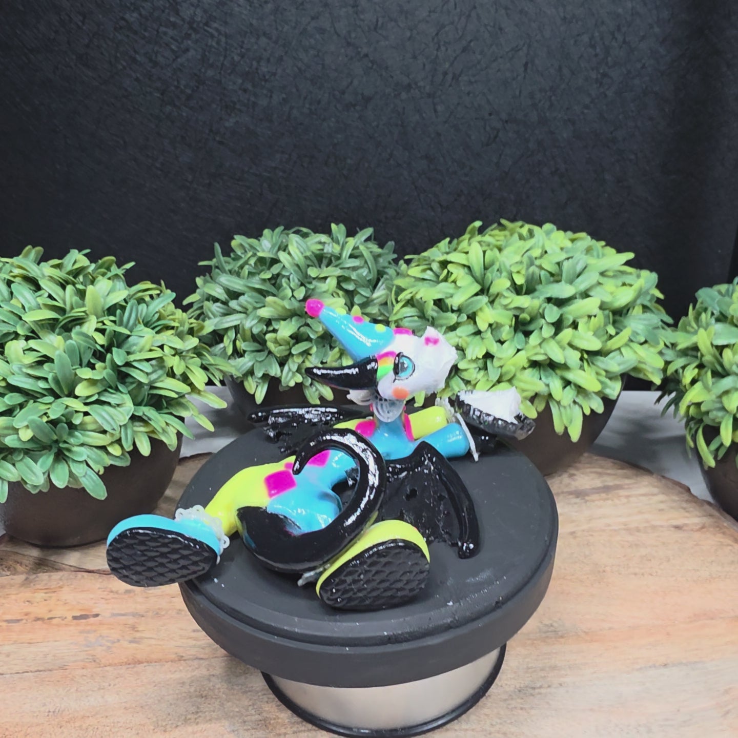 A video of a clown dragon with a cream pie on face against greenery