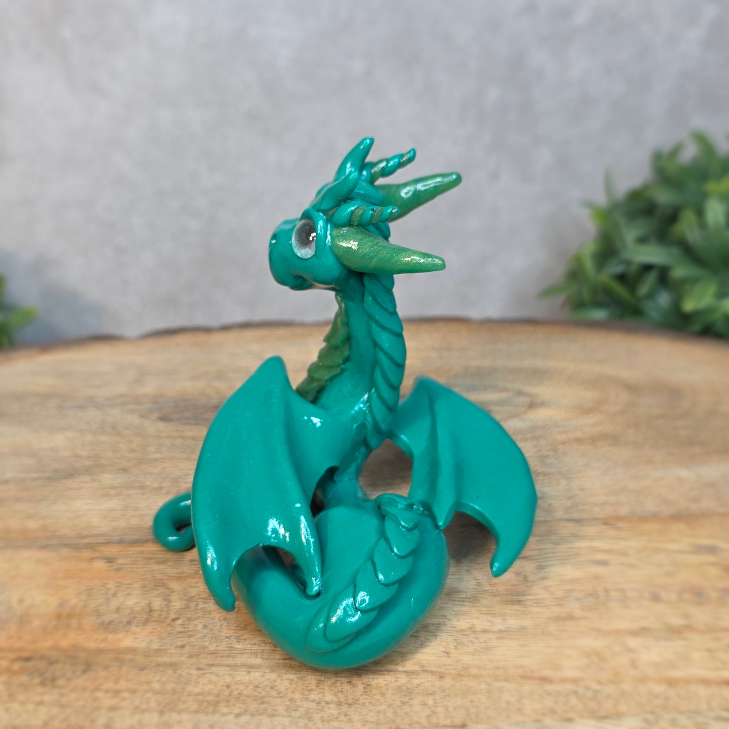 A green clay dragon against a blurred wood surface