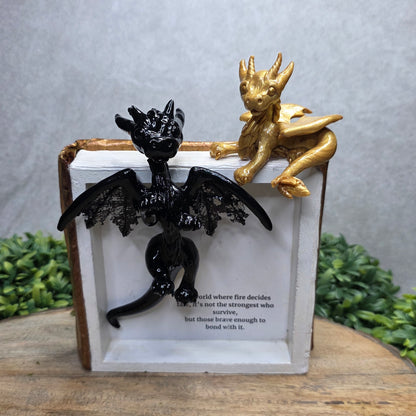 Book nook with dragons on a wood surface with greenery