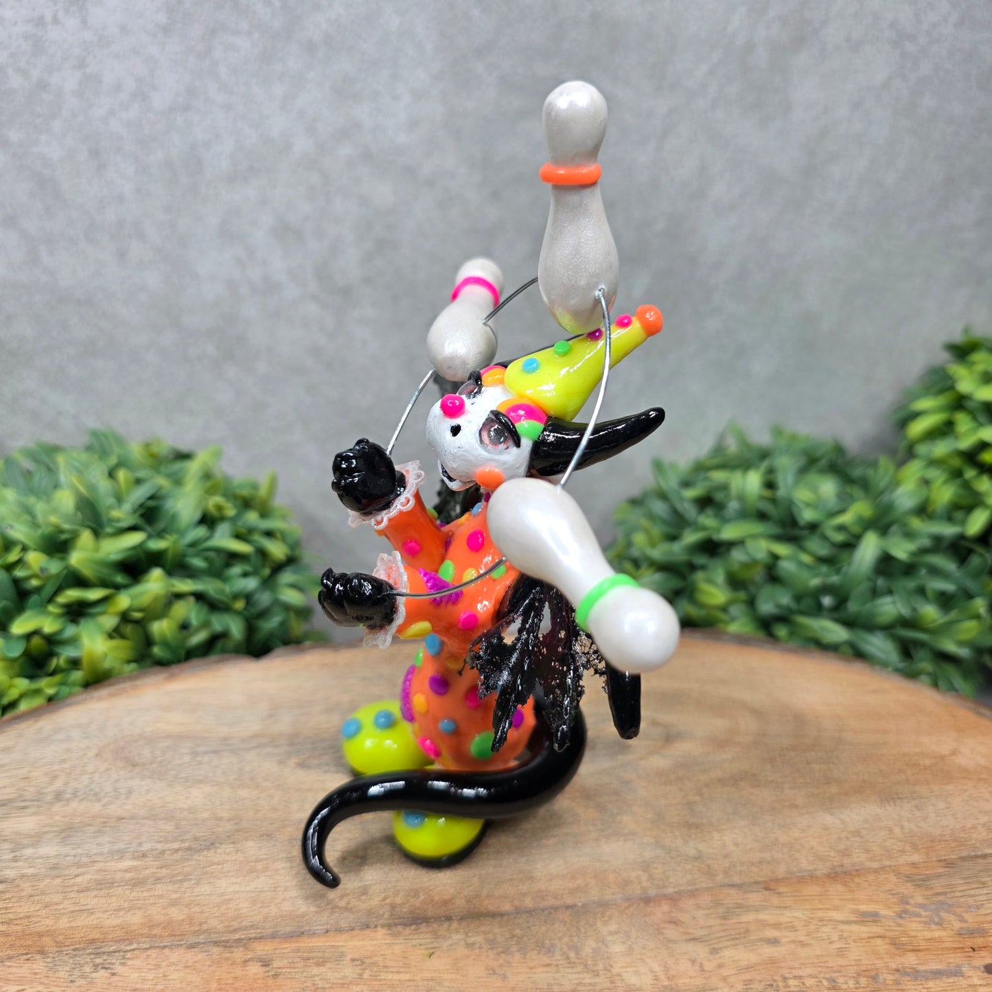 A clown dragon juggling on a wood surface with greenery