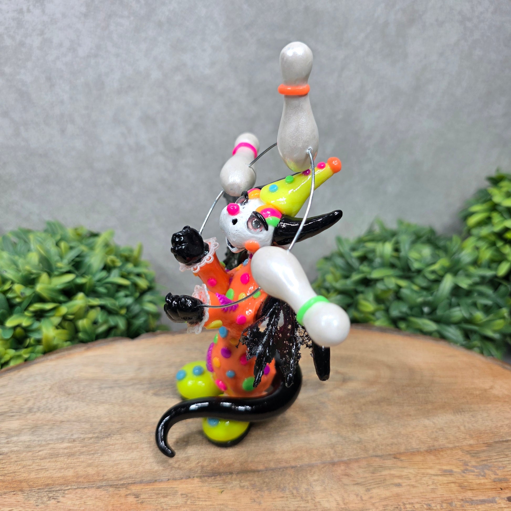 A clown dragon juggling on a wood surface with greenery