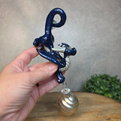 Hand holding a clay dragon with glass ornament against a blurred background