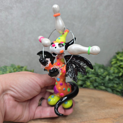 A clown dragon juggling on a wood surface with greenery