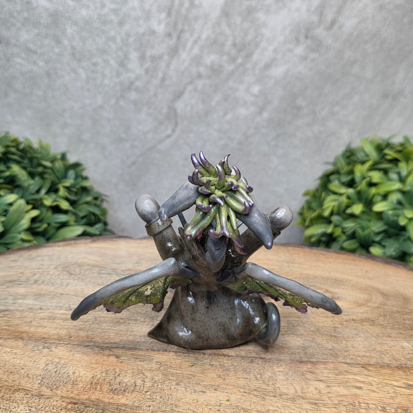 Clay dragon in costume on a wood surface with greenery.