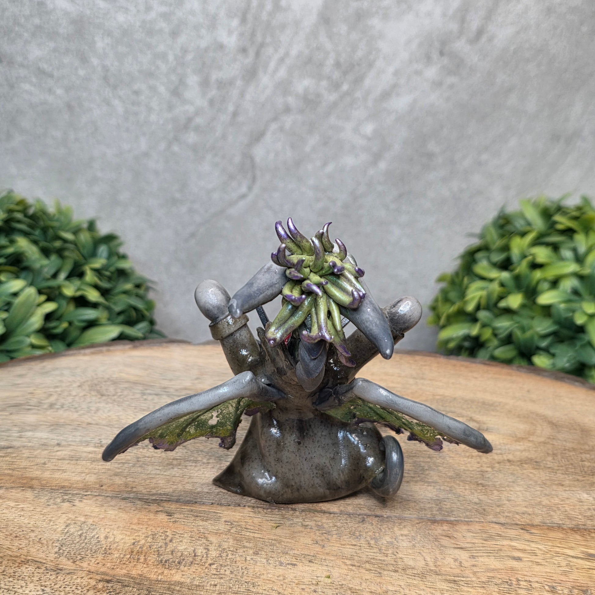 Clay dragon in costume on a wood surface with greenery.