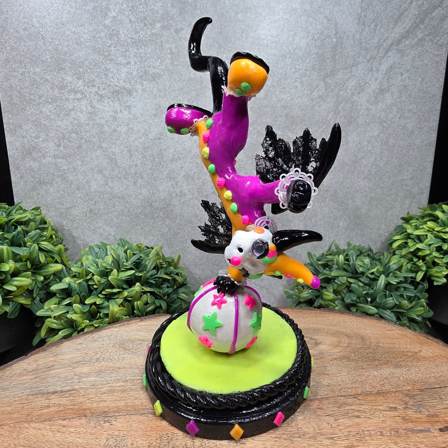A clown dragon balancing on a ball on a wood surface with greenery