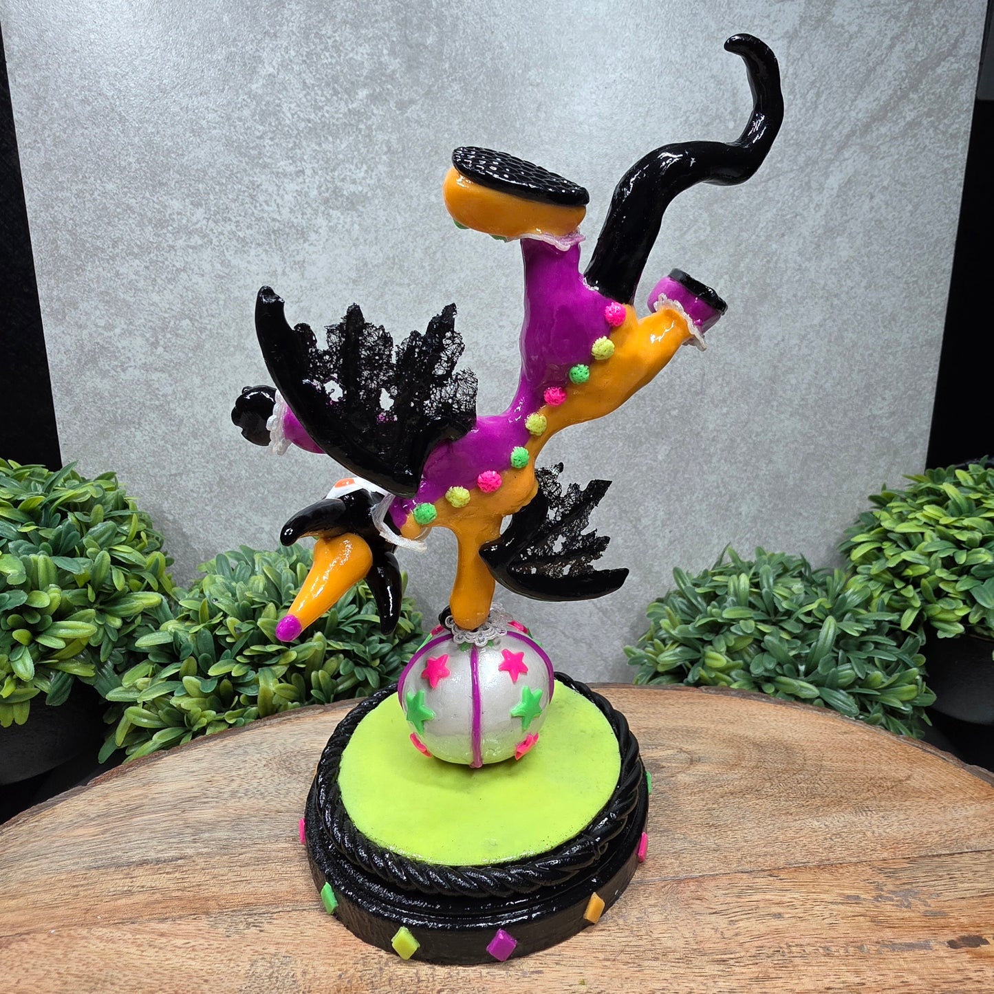 A clown dragon balancing on a ball on a wood surface with greenery