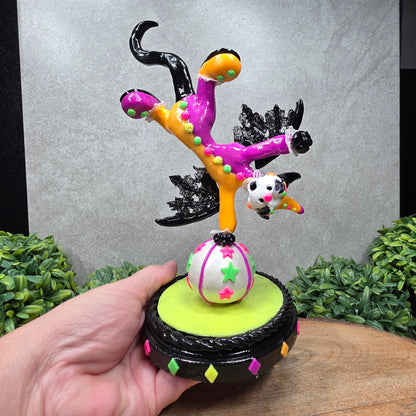 A clown dragon balancing on a ball on a wood surface with greenery