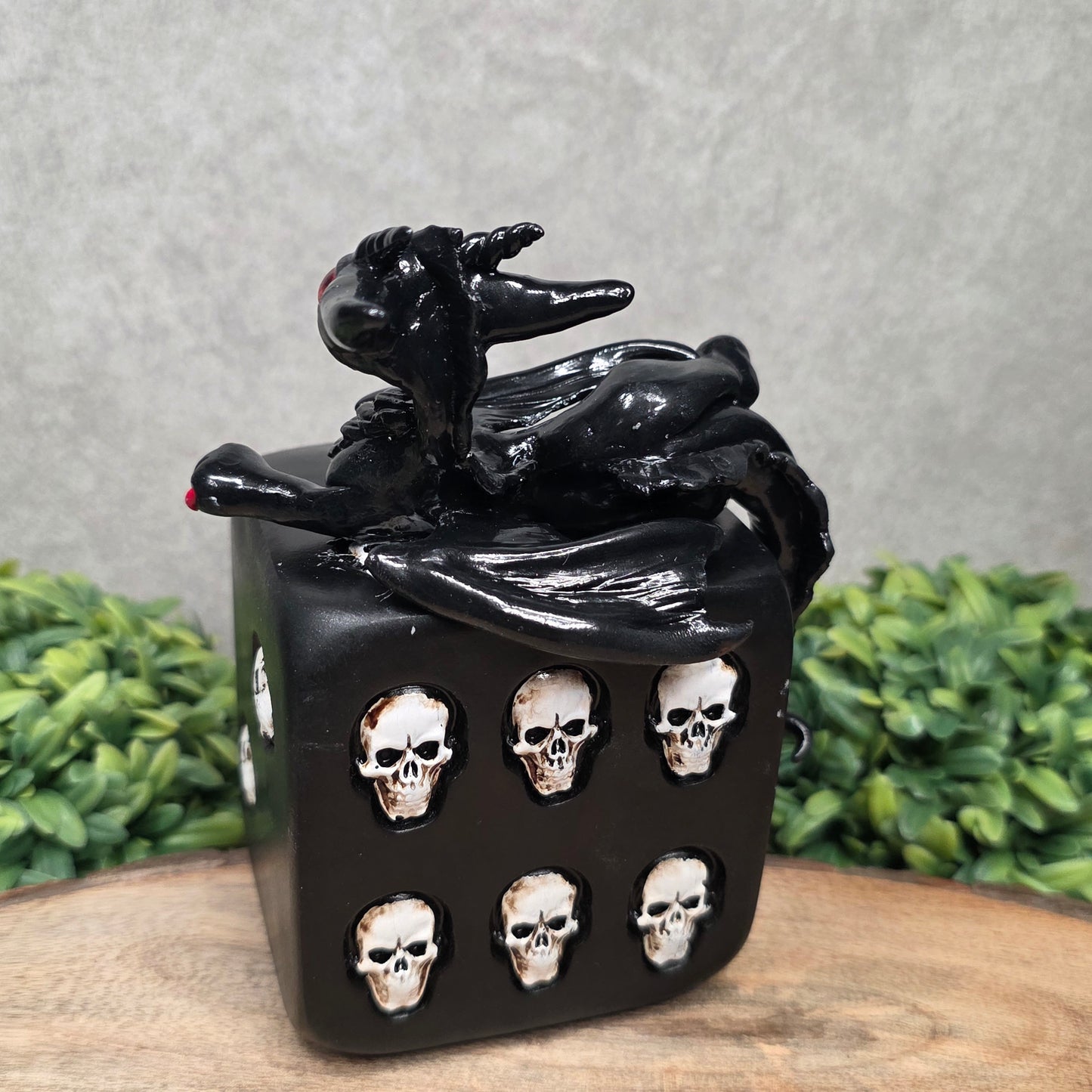 A clay dragon on a skull dice with greenery