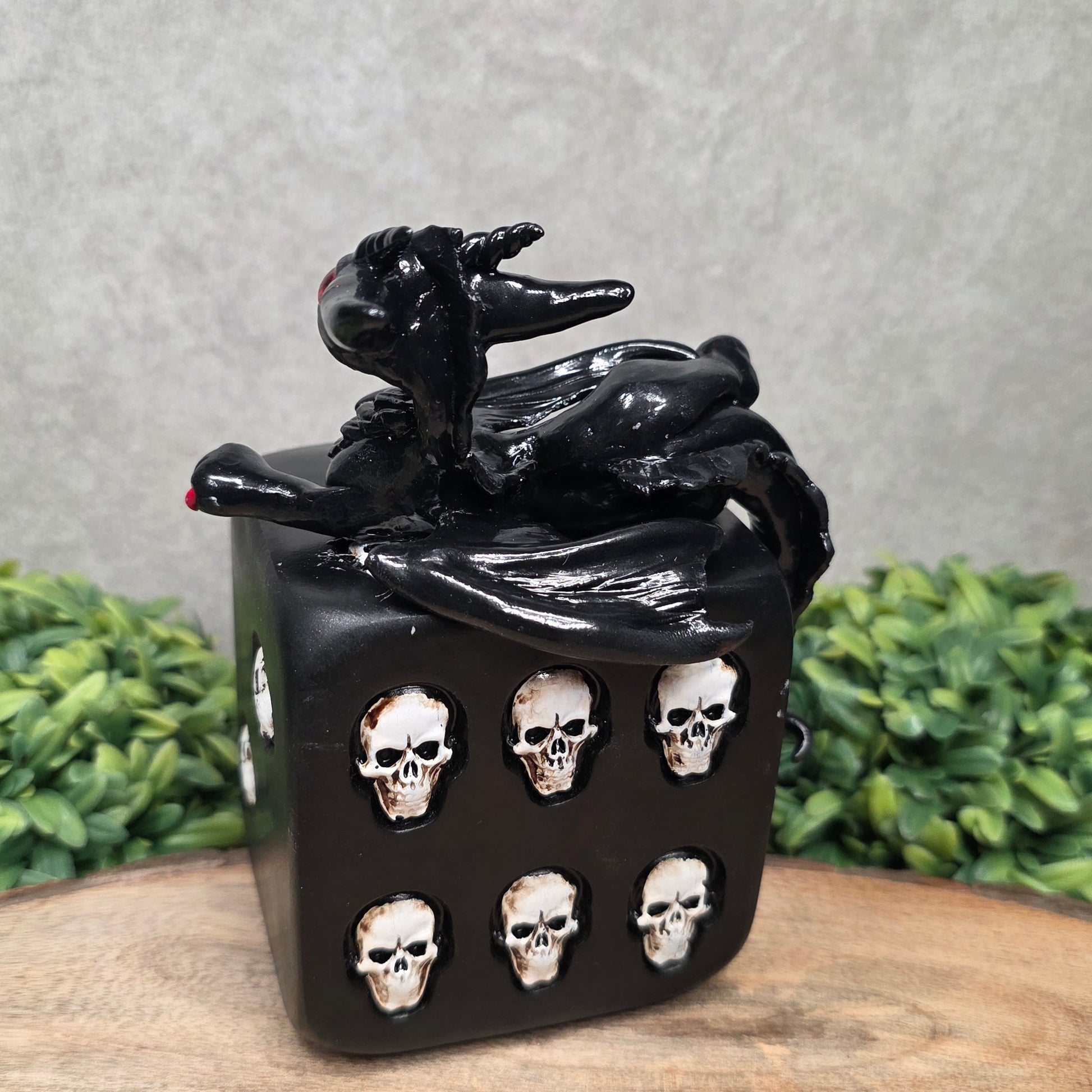 A clay dragon on a skull dice with greenery