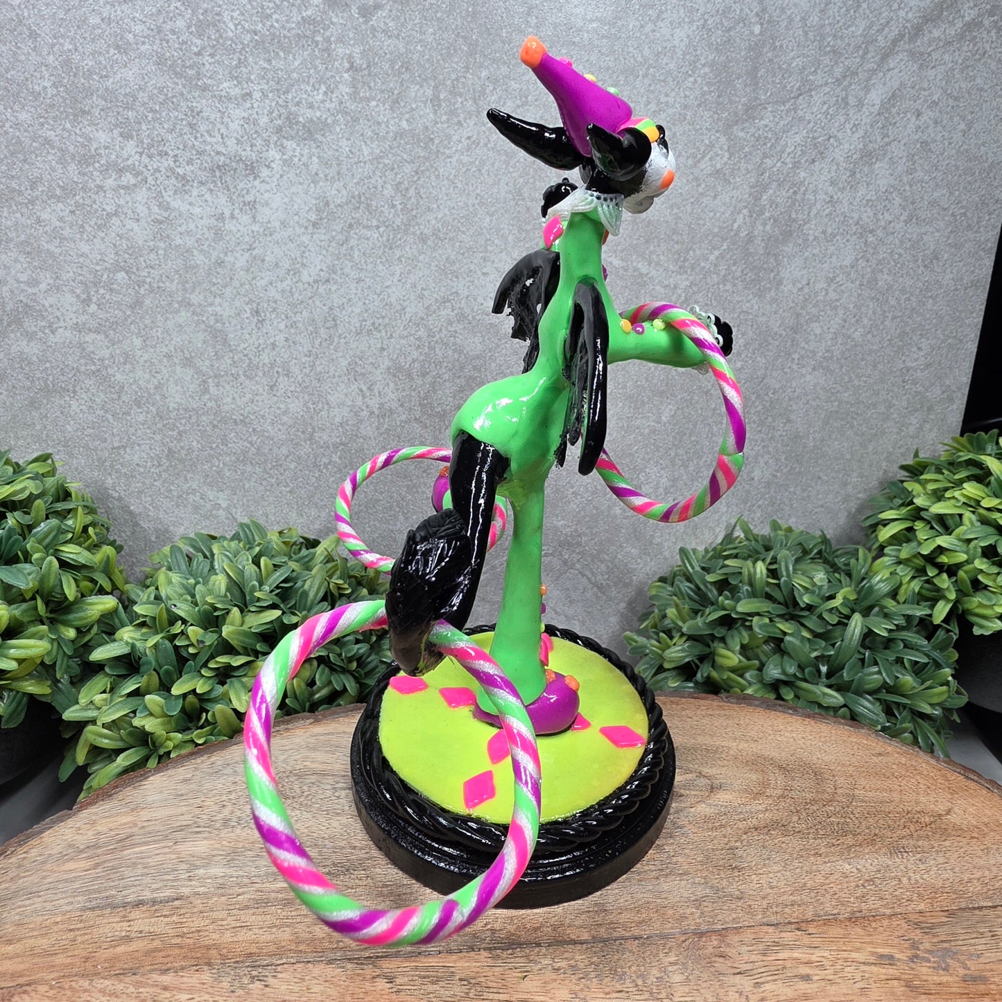A clown dragon with hoola hoops on a wood surface with greenery
