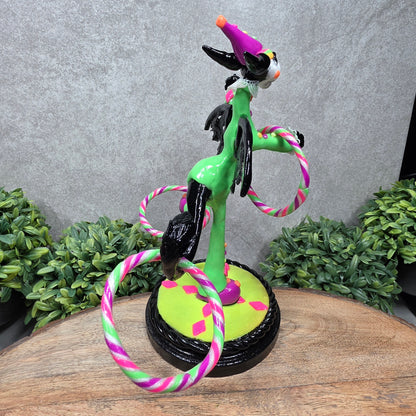 A clown dragon with hoola hoops on a wood surface with greenery