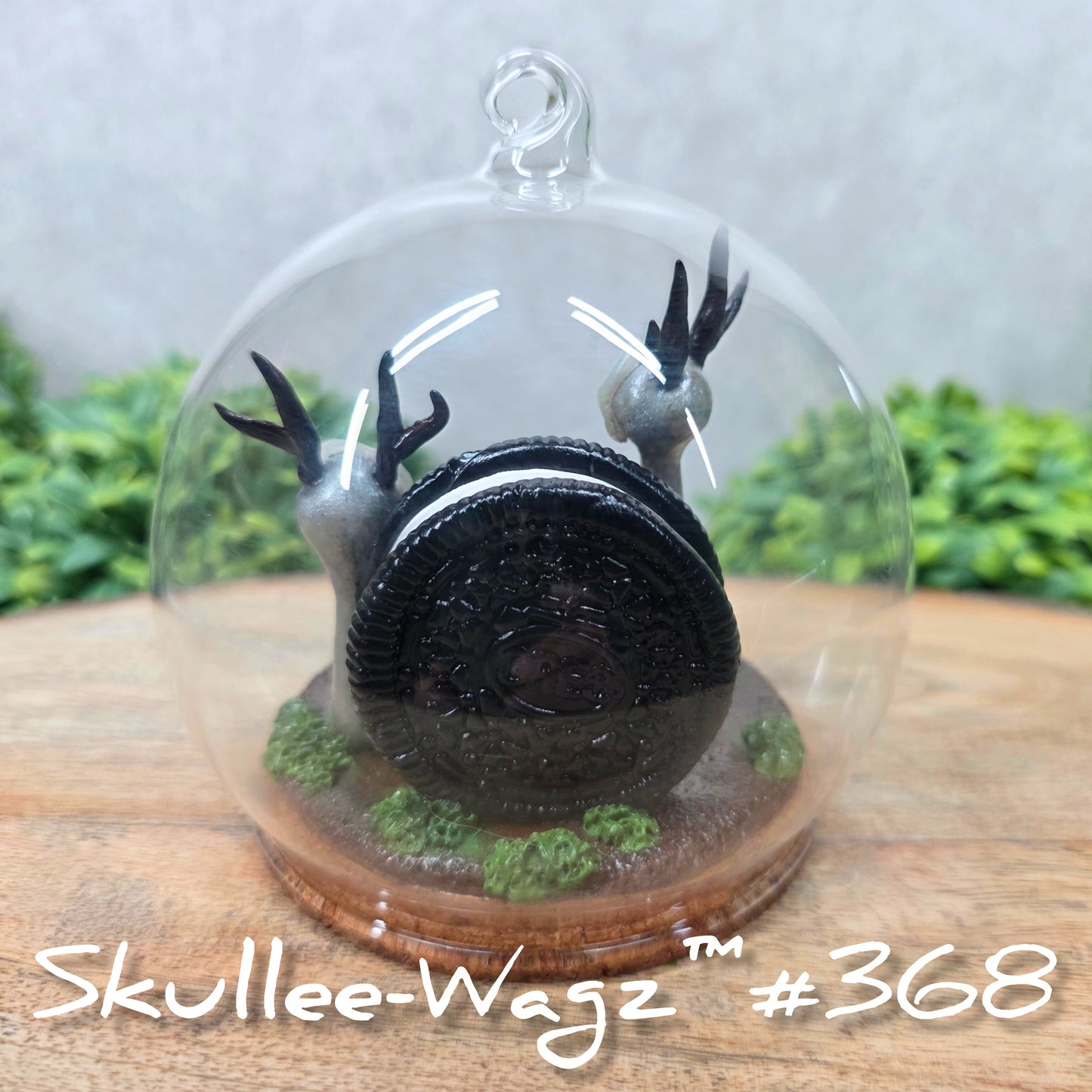 Back view of two Skullee-Wagz with cookies in a  glass dome set on a wood surface with greenery. Text reads Skullee-Wagz #368