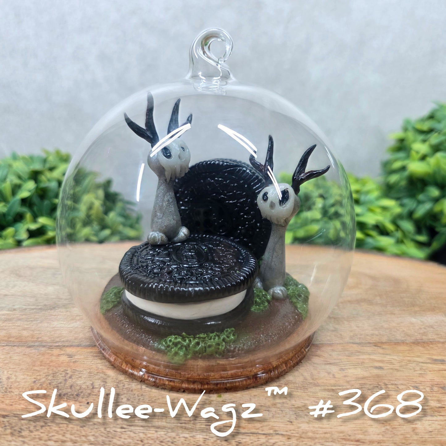 Two Skullee-Wagz with cookies in a  glass dome set on a wood surface with greenery. Text reads Skullee-Wagz #368