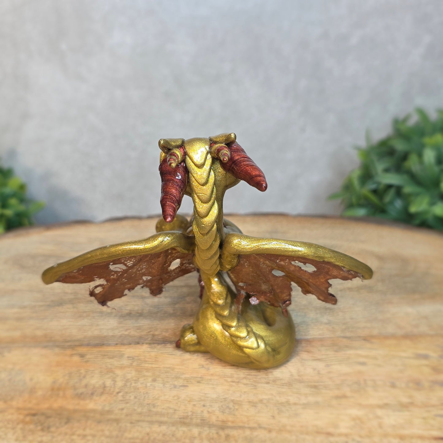 A gold and bronze clay dragon against a blurred wood surface