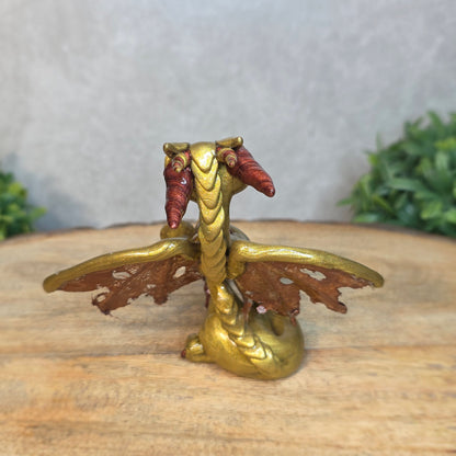 A gold and bronze clay dragon against a blurred wood surface