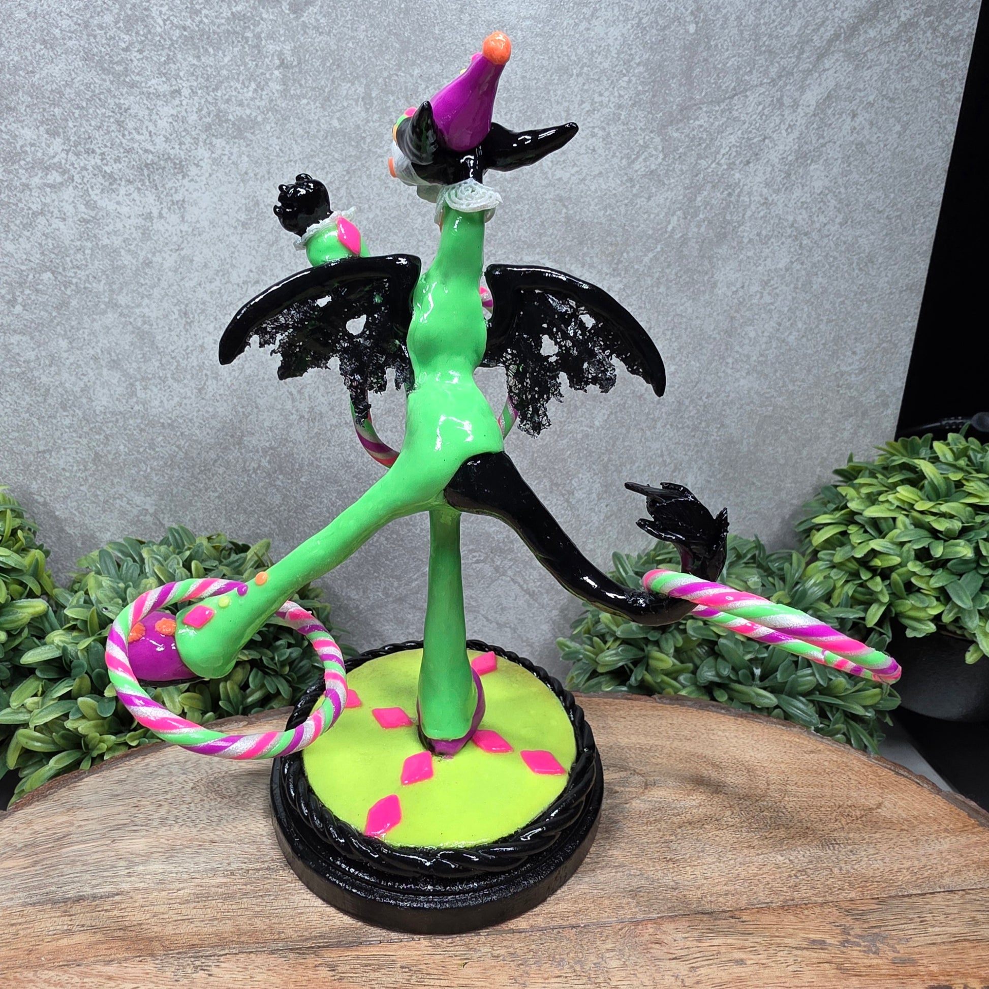 A clown dragon with hoola hoops on a wood surface with greenery