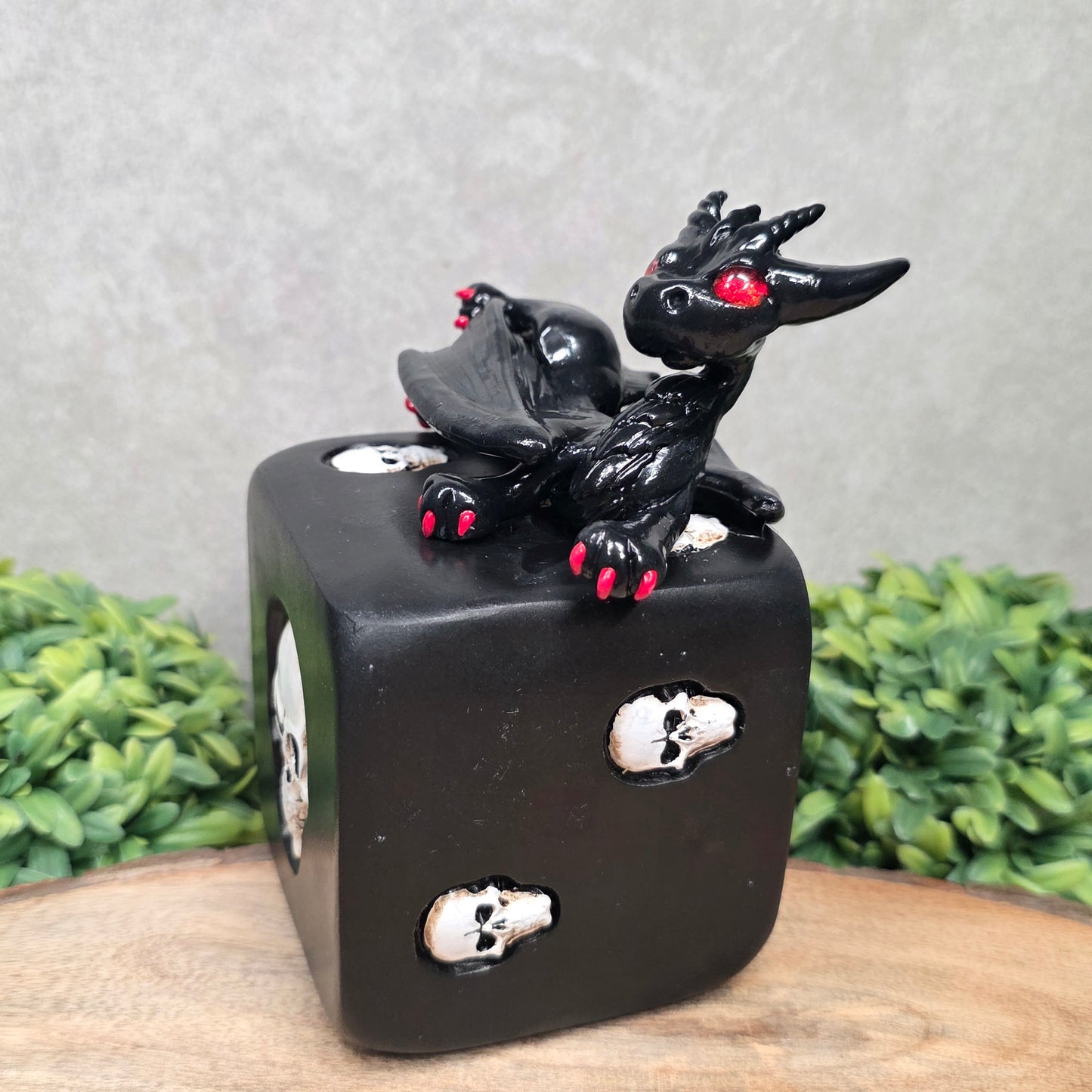 A clay dragon on a skull dice with greenery