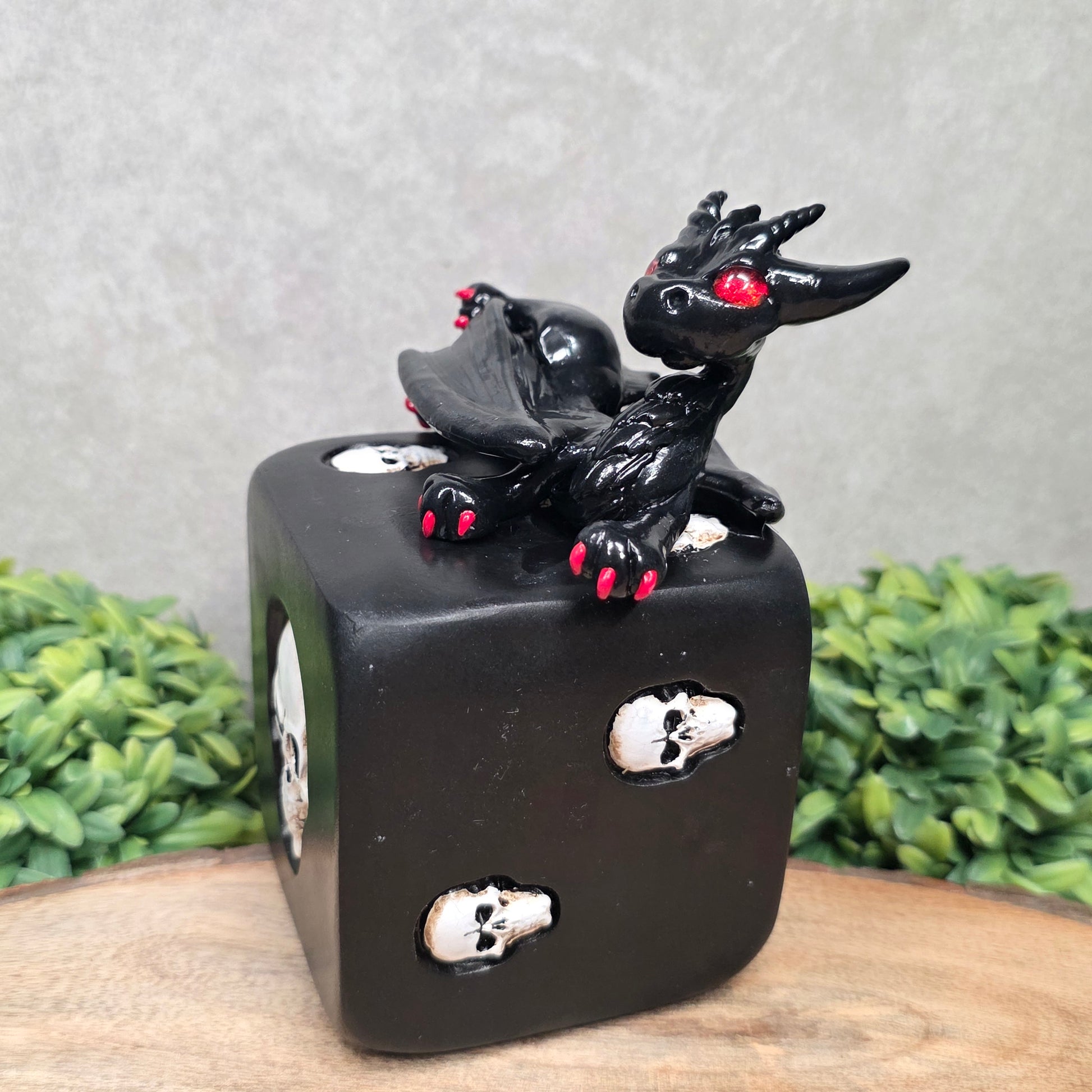 A clay dragon on a skull dice with greenery