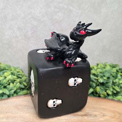 A clay dragon on a skull dice with greenery