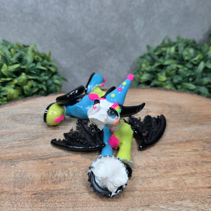 A clown dragon with cream pie on face on wood surface with greenery
