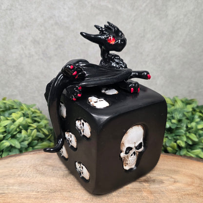 A clay dragon on a skull dice with greenery