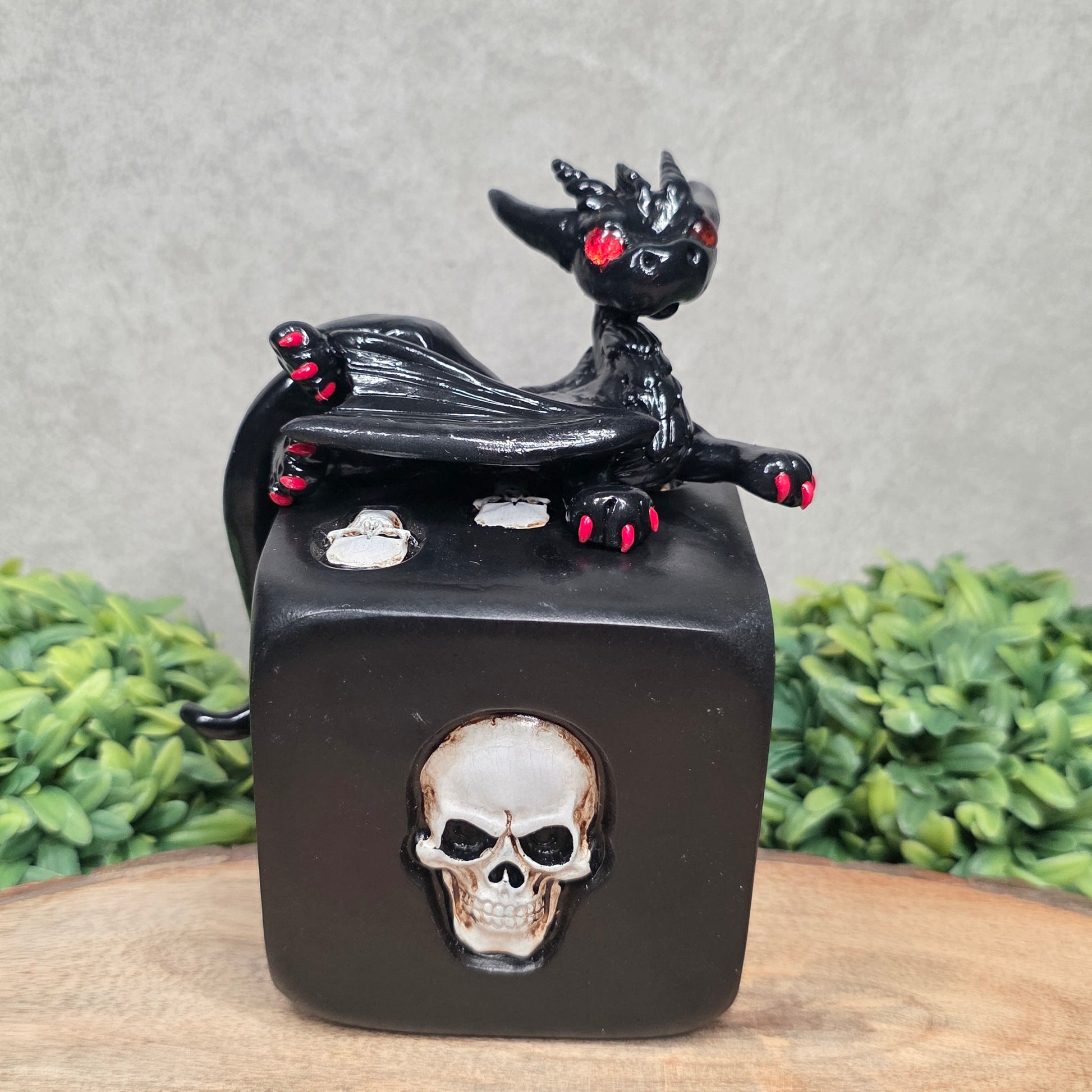 A clay dragon on a skull dice with greenery