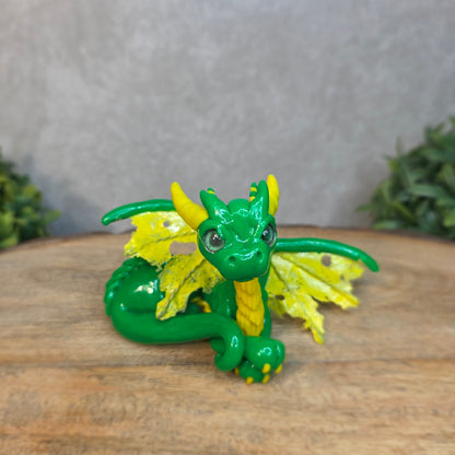 A green and yellow dragon against a blurred wood surface