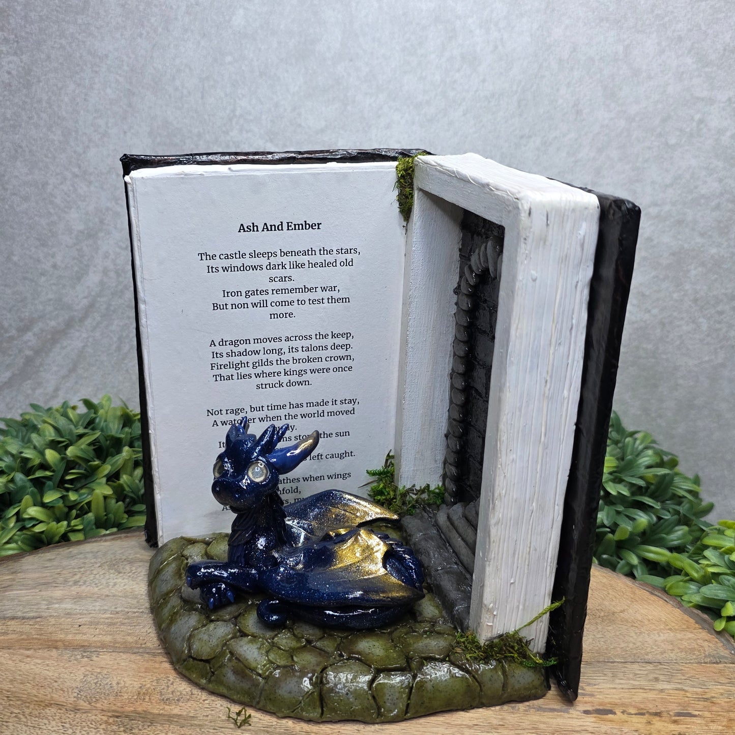 Book nook with dragon on a wood surface with greenery