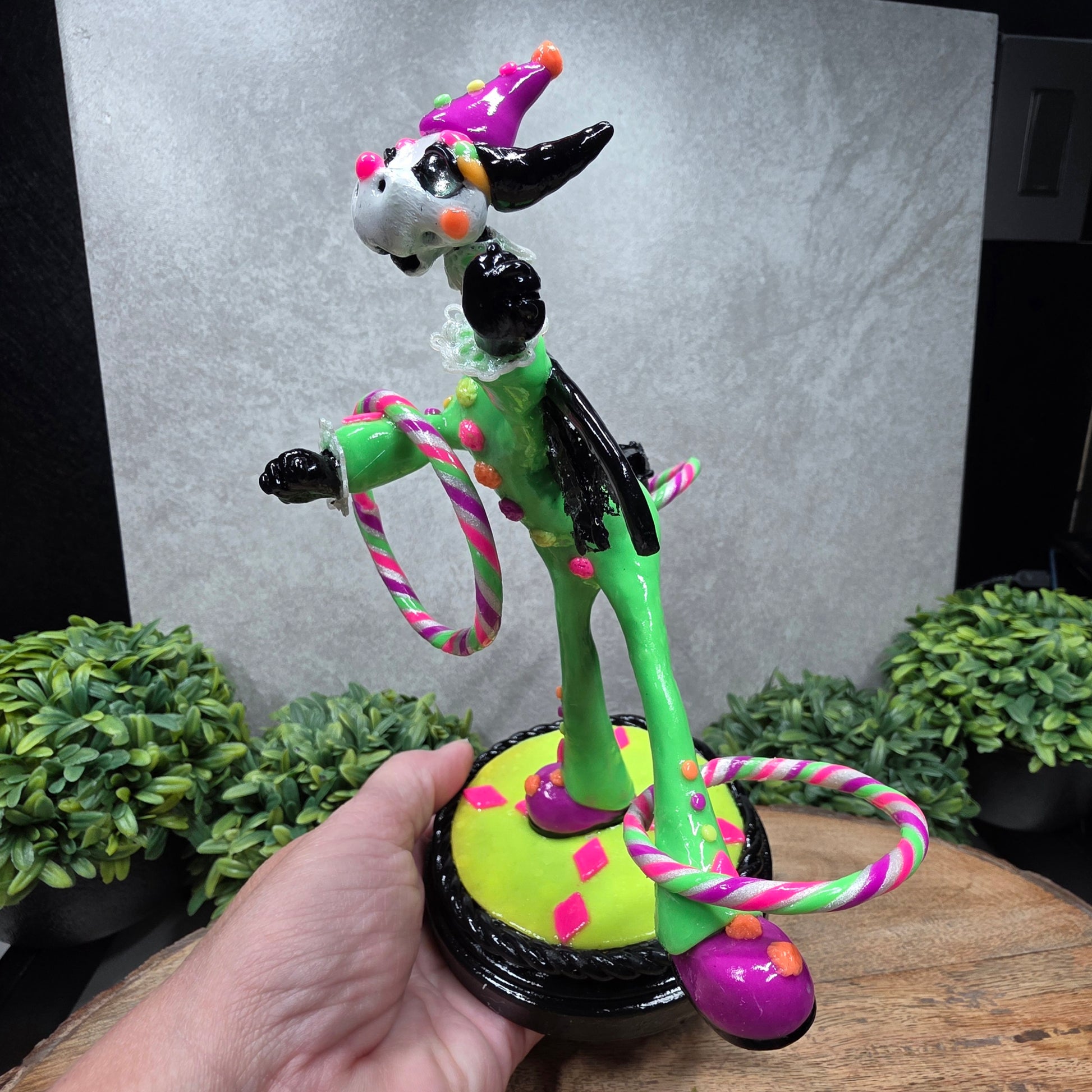 A clown dragon with hoola hoops on a wood surface with greenery