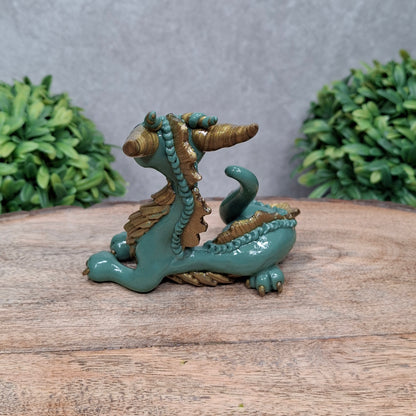 A clay dragon against a wood background with greenery